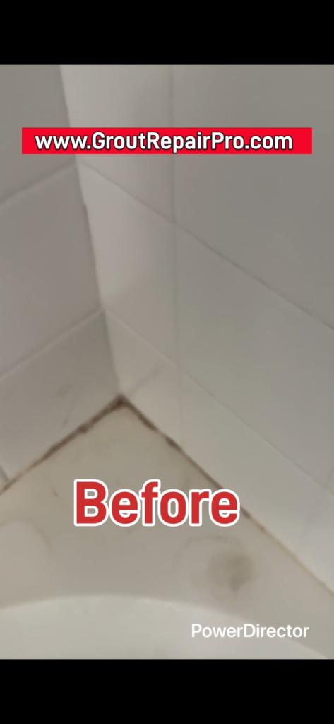 Stained tub ledge and deteriorated grout around the shower soap dish.