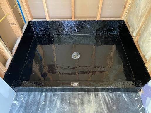 Traditional hot mop shower pan installation with layers of black asphalt