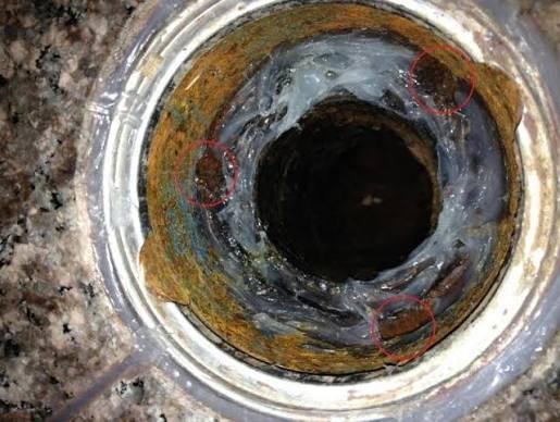 Real world look down a three piece shower drain collar showing clogged or open weep holes inside the flange
