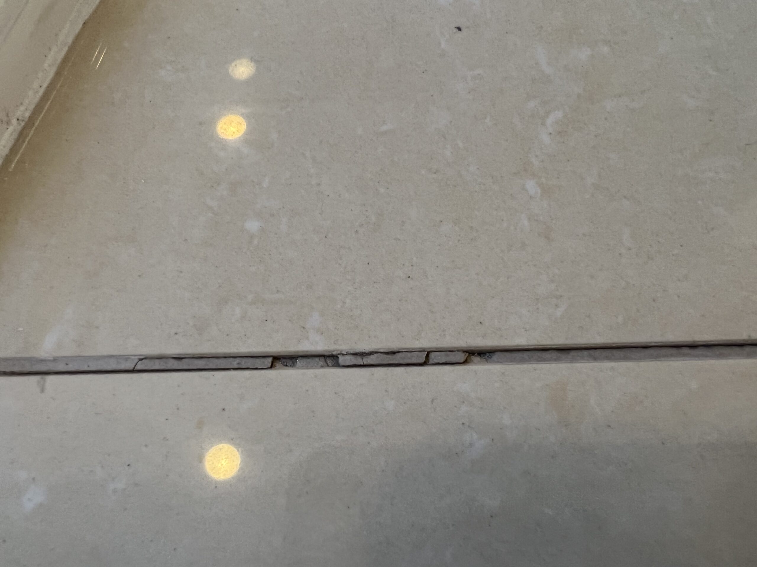 Cracked grout joints running through marble tub surround panels