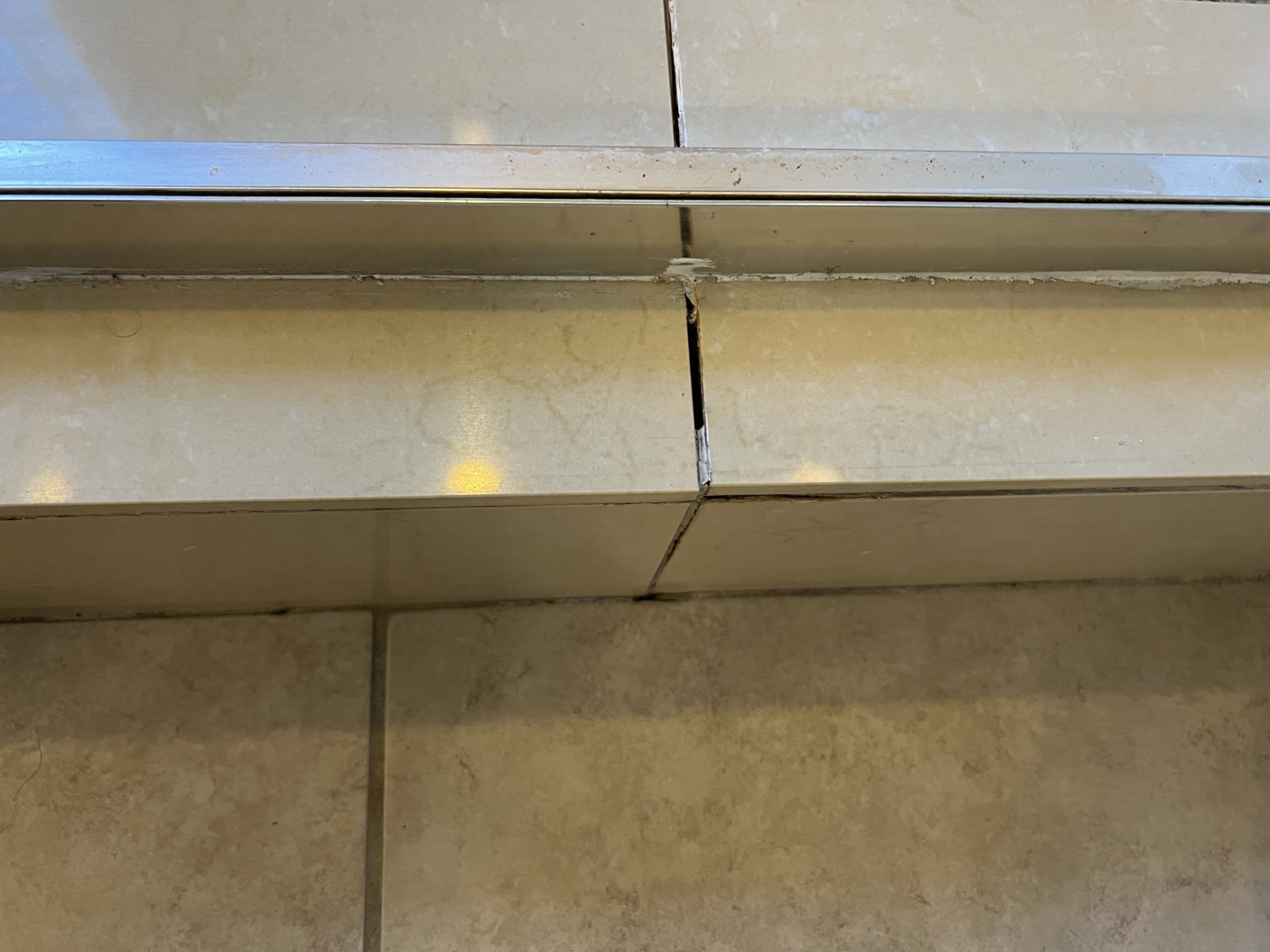 Missing and cracked grout at the base of a shower curb