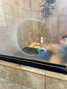 Professional glass shower door deep cleaning to strip hard water spots and mineral scale deposits