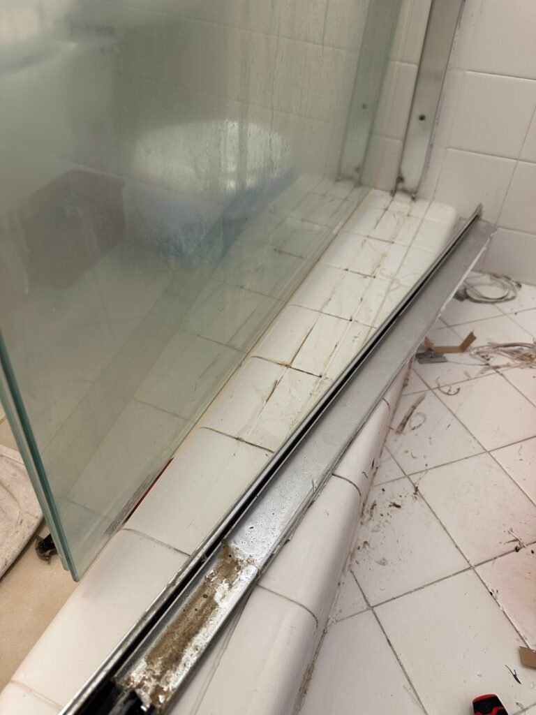 Professional shower restoration in Folsom removing lower metal glass channel for mold remediation