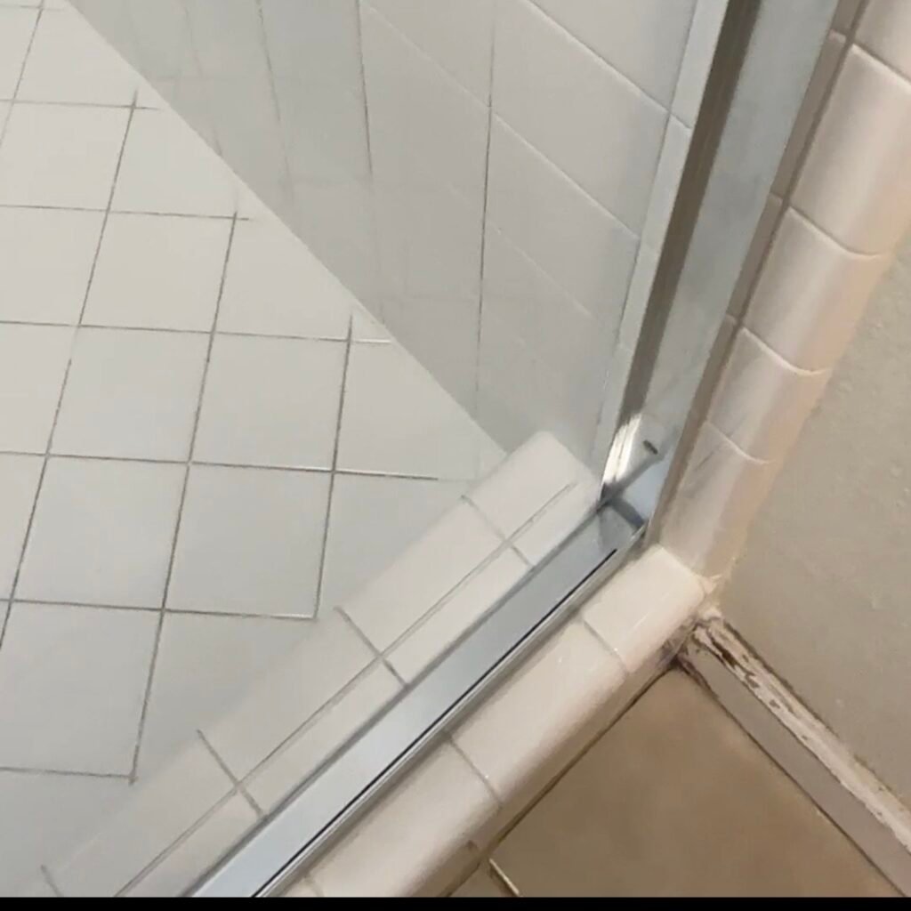Completed shower restoration with sealed tile floor perimeter and clean grout lines